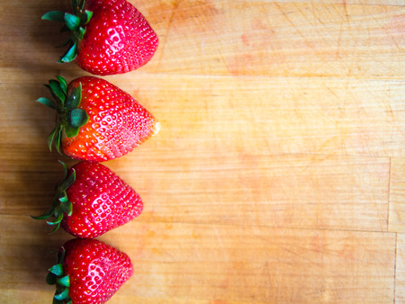 Arranged row of strawberries on a wooden board with empty spaceの写真素材