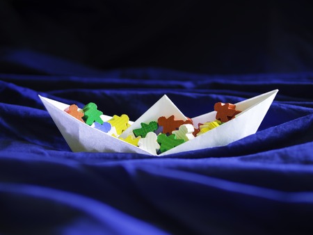 Immigration emigration migration conceptualization, white paper boat full of colorful meeples, refugee crisis topic illustration and social issues symbolの写真素材