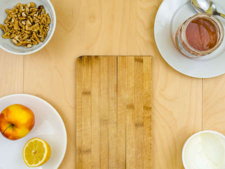Nutritious healthy ingredients around board, apple, cheese, walnuts and honeyの写真素材