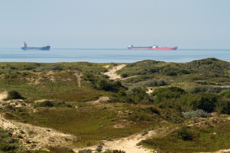 Industrial ships on sea with dunes の写真素材