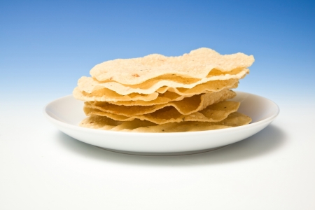 Plate of fresh pappadums on a blue studio background.の写真素材