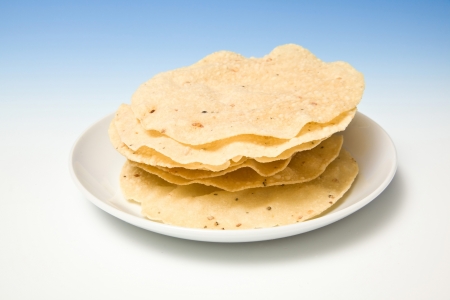 Plate of fresh pappadums on a blue studio background.の写真素材