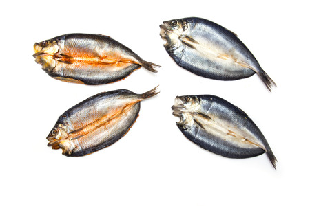 Dyed and non-dyed Scottish smoked kippers isolated on a white studio background.