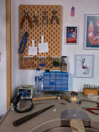 Workplace of an artisan jeweler in her workshop with various tools and the workbench.