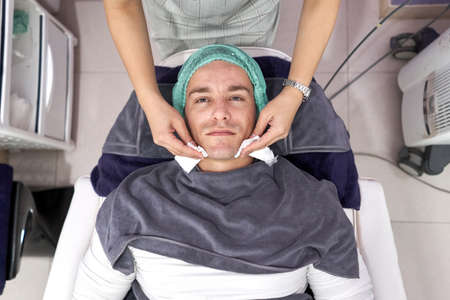Top view of a man lying down on a stretcher ready for a facial beauty treatment