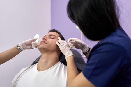 Doctor giving botox treatment for facial rejuvenation to a man