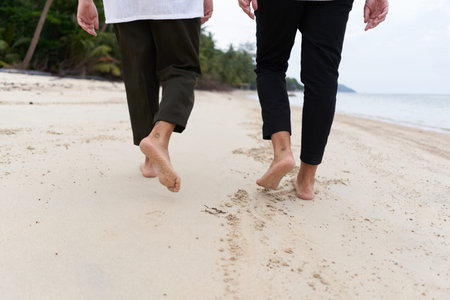 Barefoot legs of two men walking on a tropical beachの写真素材