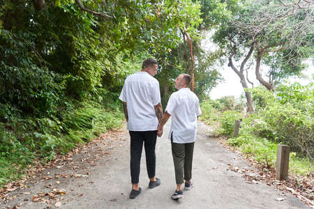 Gay couple strolling along a rainforest path holding hands