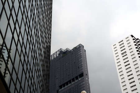 Facade of a modern building surrounded by skyscrapers reflecting on it