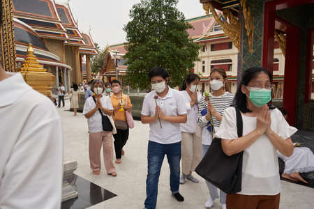 Bangkok, Thailand, february, 16, 2022: group of people praying while standing outside a buddhist...