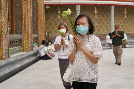 Bangkok, Thailand, february, 16, 2022: Two women with flowers praying during a Buddhist festival in...