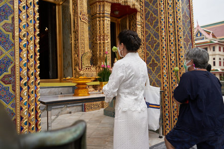 Bangkok, Thailand, february, 16, 2022: woman in white dress praying in a buddhist temple