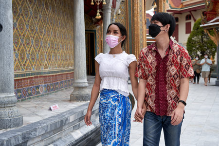 Multiethnic couple with mask visiting a buddhist temple