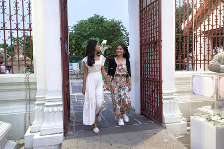 Friends walking while holding hands inside a buddhist temple