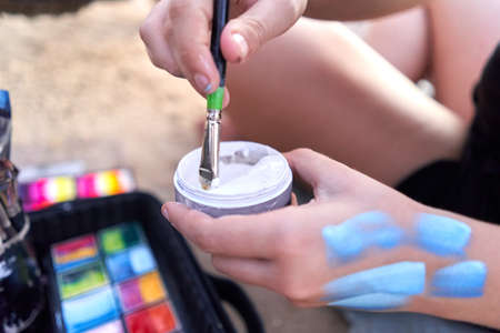 Artist dipping his brush in paint sitting on a beachの写真素材