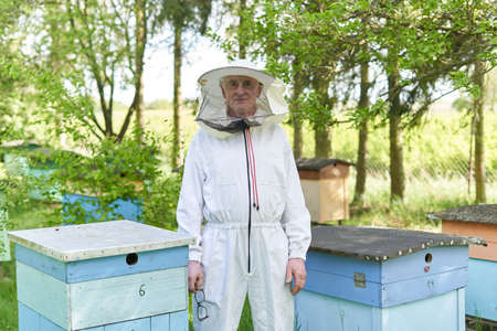 Portrait of an aged beekeeper next to beehivesの写真素材