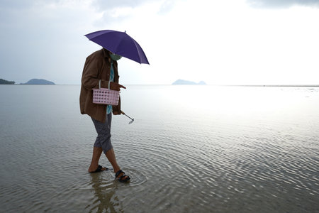 Ko Phangan, Thailand, March 15, 2022: woman with mask collecting clamsのeditorial素材