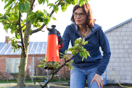 Woman fumigating plants in a home gardenの写真素材