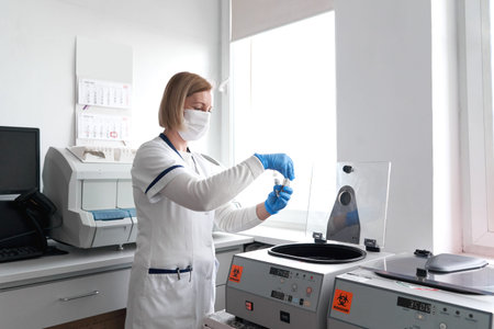 Doctor holding a tube with a sample while using a centrifuge in a hospital