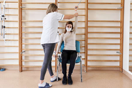 Physiotherapist rehabilitating a patient sitting in a chairの写真素材