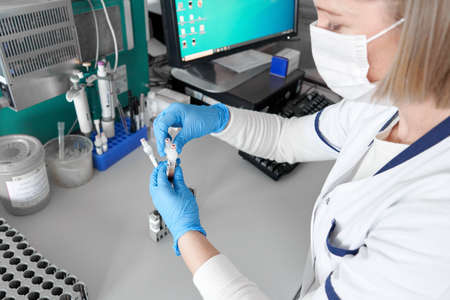Worker with blood samples next to a centrifuge reaction vessel