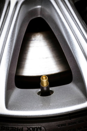 Close-up of a tire valve on car wheel with visible aloy wheel and fragment of brake disc 
