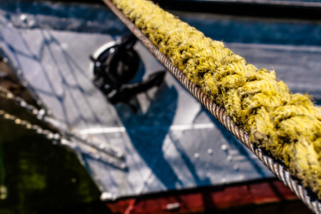 Thick yellow hawser, mooring line with blurred visible fragment of the ship, anchor visible の写真素材