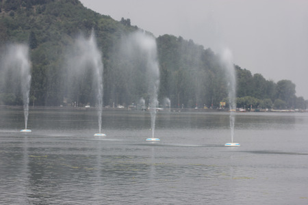 Dal Lake, Srinagar, Kashmir, with beautiful Boulevard road winding along banks, lined by poplar trees, Shankeracharya hill in the background, tall fountainsの写真素材