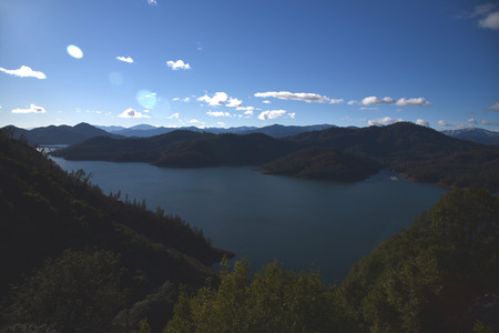 Lake Shasta near McCloud arm of Shasta .with beautiful clear water, reddish rust color shores due to high iron content, surrounded by forest covered slopes.の写真素材