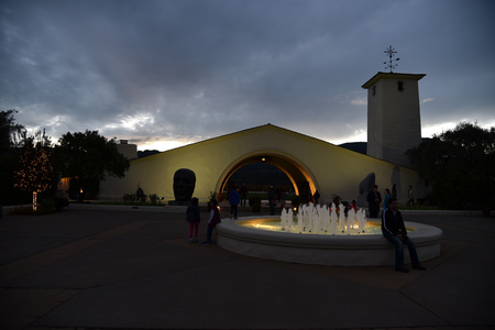 Sunset view in Napa Valley with black and white clouds above undulating mountain top, pond with fountains and Robert Mondavi Winery building in foreground.のeditorial素材