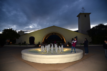 Sunset view in Napa Valley with black and white clouds above undulating mountain top, pond with fountains and Robert Mondavi Winery building in foreground.のeditorial素材
