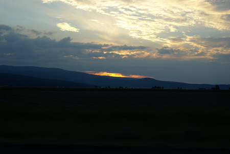 Sunset view Klamath county, Oregon, USA, with golden cloud patches above undulating range, with patches of dark clouds, and clear sky.の写真素材