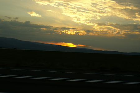 Sunset view Klamath county, Oregon, USA, with golden cloud patches above undulating range, with patches of dark clouds, and clear sky.の写真素材