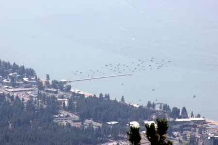 View of Lake Tahoe, buildings and shoreline from upper deck of Heavenly Gondola, providing panoramic view of low isolated clouds and distant mountain ranges.の写真素材