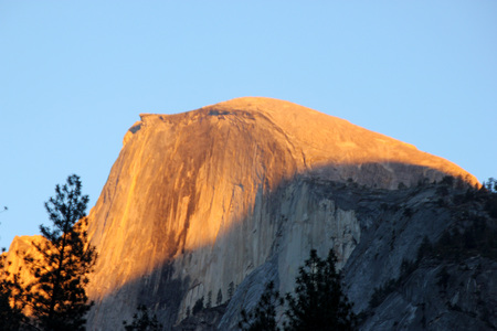 Sunset on Half Dome, Yosemite, view from Curry Village Parking, darker orange yellow color rays at 16.46, November 24, on upper half of the dome slowly changing to finally redのeditorial素材