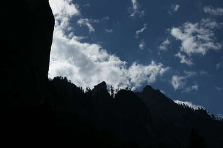 Evening view of Yosemite valley, Yosemite National Park in the western Sierra Nevada mountains of Northern California, USA with sun having gone behind mountain peak, thin clouds in clear blue sky.の写真素材
