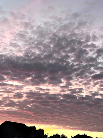 Sunset in Fremont, California early March with scattered dark clouds over the horizon broken up by...
