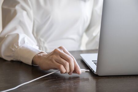 Hand of a woman plugging the cord into the USB of the personal computer