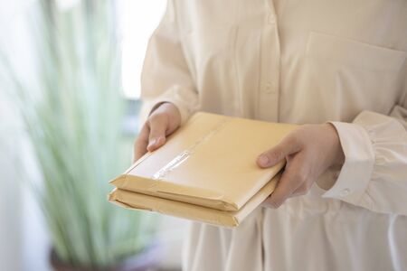 Young woman holding mail in the roomの写真素材