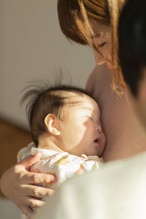 Dad and mom holding a baby in a bright room