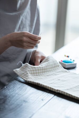 Hand of a young woman sewing in a roomの写真素材
