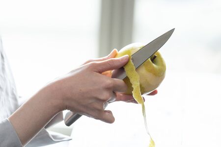 Young woman peeling an apple in the room