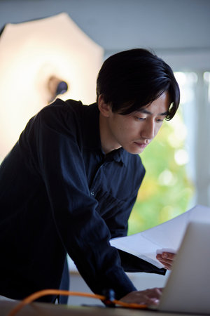 Japan photographer man operating laptop in photo studioの写真素材