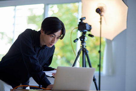 Japan photographer man operating laptop in photo studioの写真素材