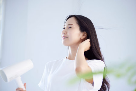 Summer image of healthy Japan woman drying her hair with a hairdryerの写真素材
