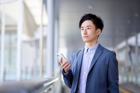 Spring image of a Japan businessman in his 20s working using a smartphoneの写真素材