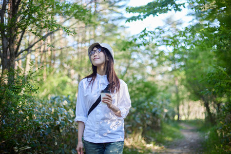 Japan woman in her 30s enjoying forest bathing while relaxing in the summer forest