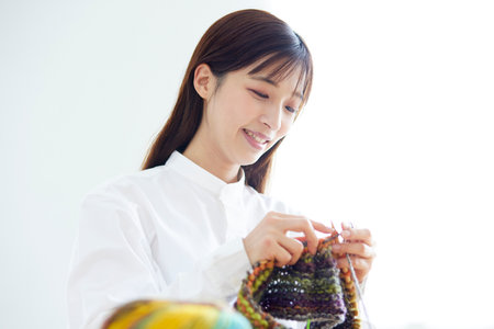 Japan woman in her 30s knitting yarn as a hobby handicraft in the living roomの写真素材