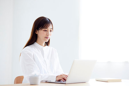 Japan woman in her 30s learning online using a computer in the living roomの写真素材