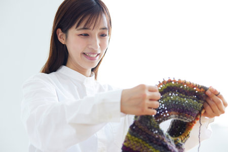Japan woman in her 30s knitting yarn as a hobby handicraft in the living roomの写真素材